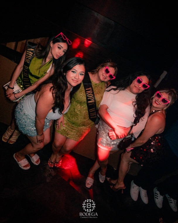 A birthday group in sashes and party glasses posing together at Bodega