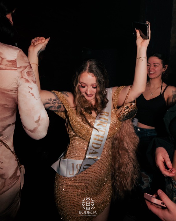 A birthday guest in a sash dancing on the Bodega floor