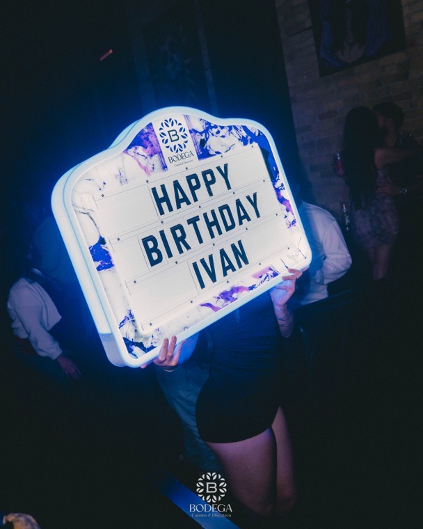 A personalised lit birthday sign glowing above the crowd